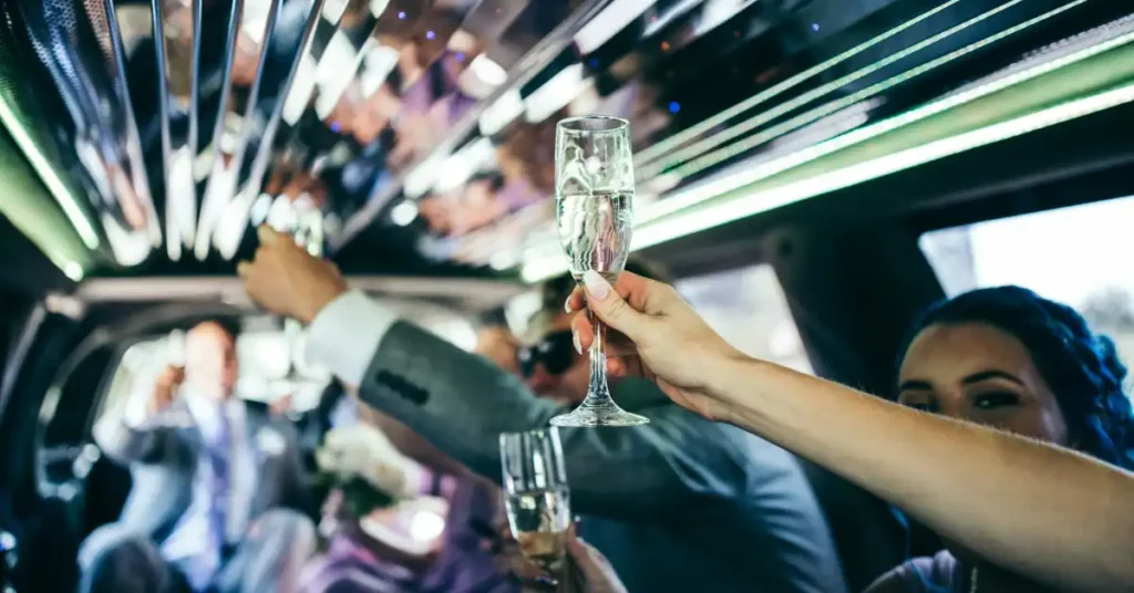 Foto de uma celebração dentro de uma limousine com pessoas levantando taças de champanhe