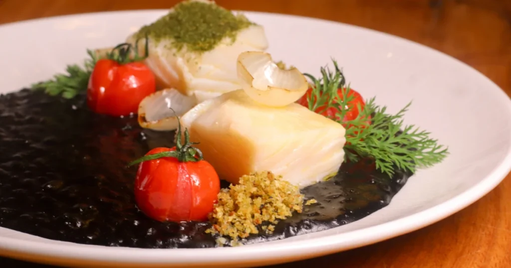 Foto do prato com Bacalhau confitado com risoto de tinta de lula