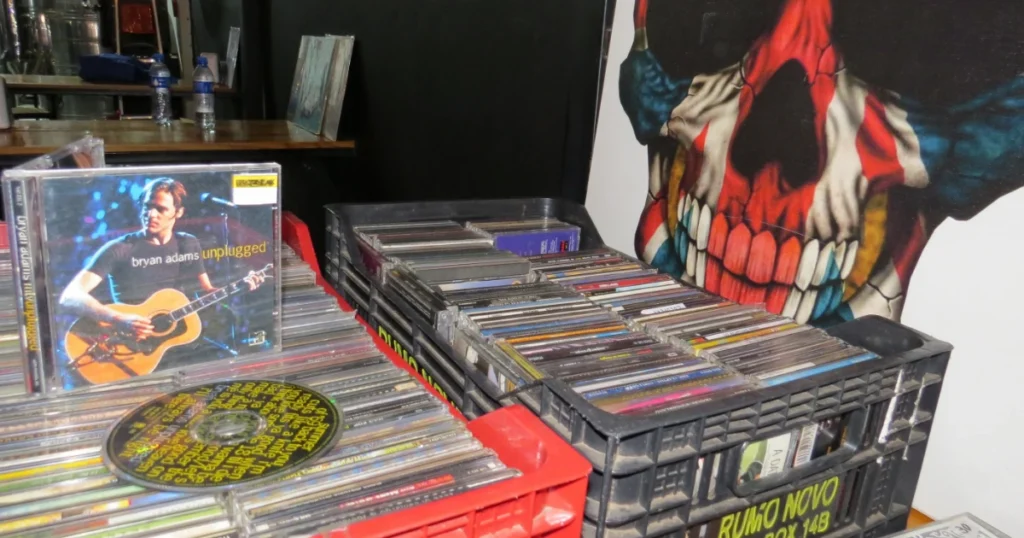 Foto com vários cds em caixas com destaque para um cd do Bryan Adams, unplugged