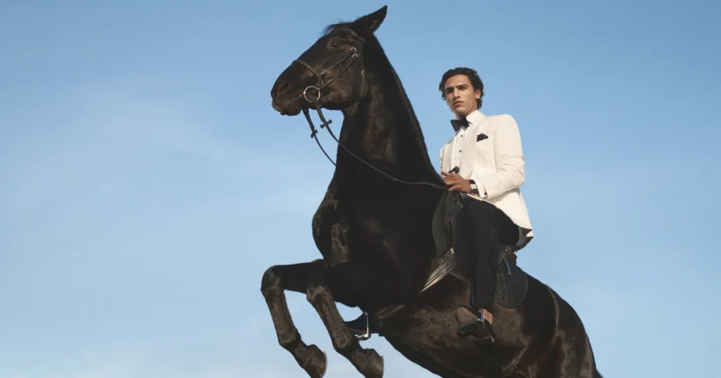 Um homem com terno branco em cima de um cavalo preto
