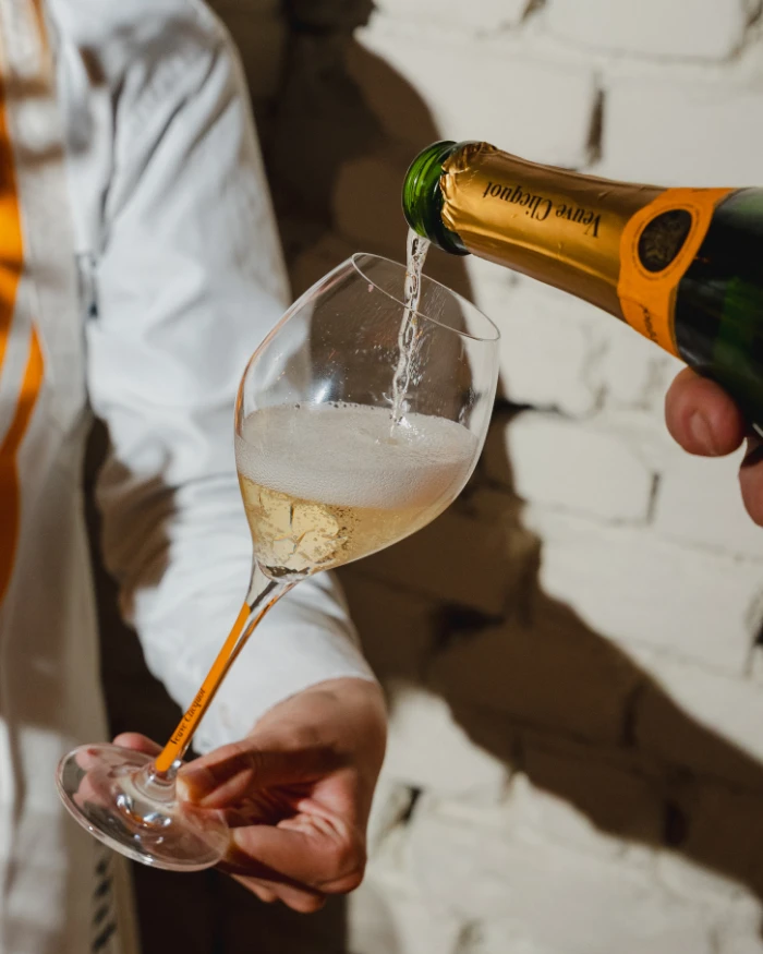 Foto de uma pessoa colocando um champagne da Veuve Clicquot em uma taça