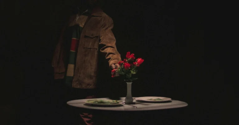 Foto de um homem organizando uma mesa com uma flor vermelha no centro