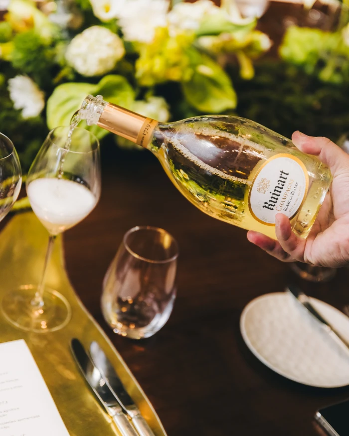 Foto de uma pessoa colocando um champagne Ruinart em uma taça
