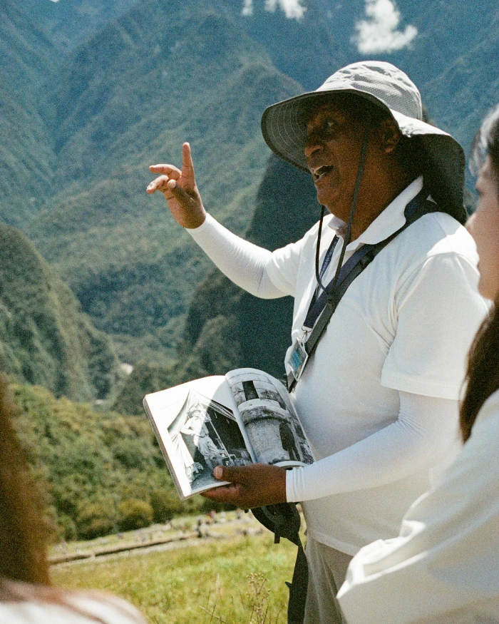 Um homem mostrando um folheto para duas mulheres em Machu Pichu, no Peru