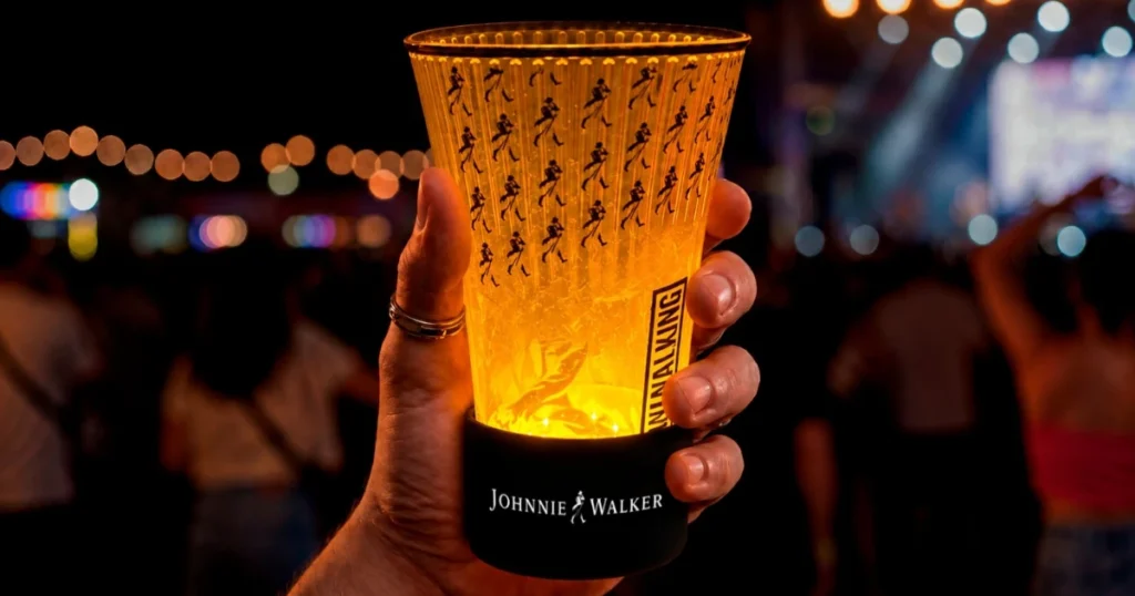 Uma ilustração de uma mão segurando o copo da Johnnie Walker para o Rock in Rio 2026