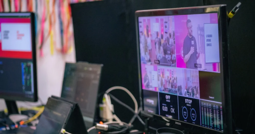 Foto de um monitor com vários feeds de câmeras filmando uma palestra